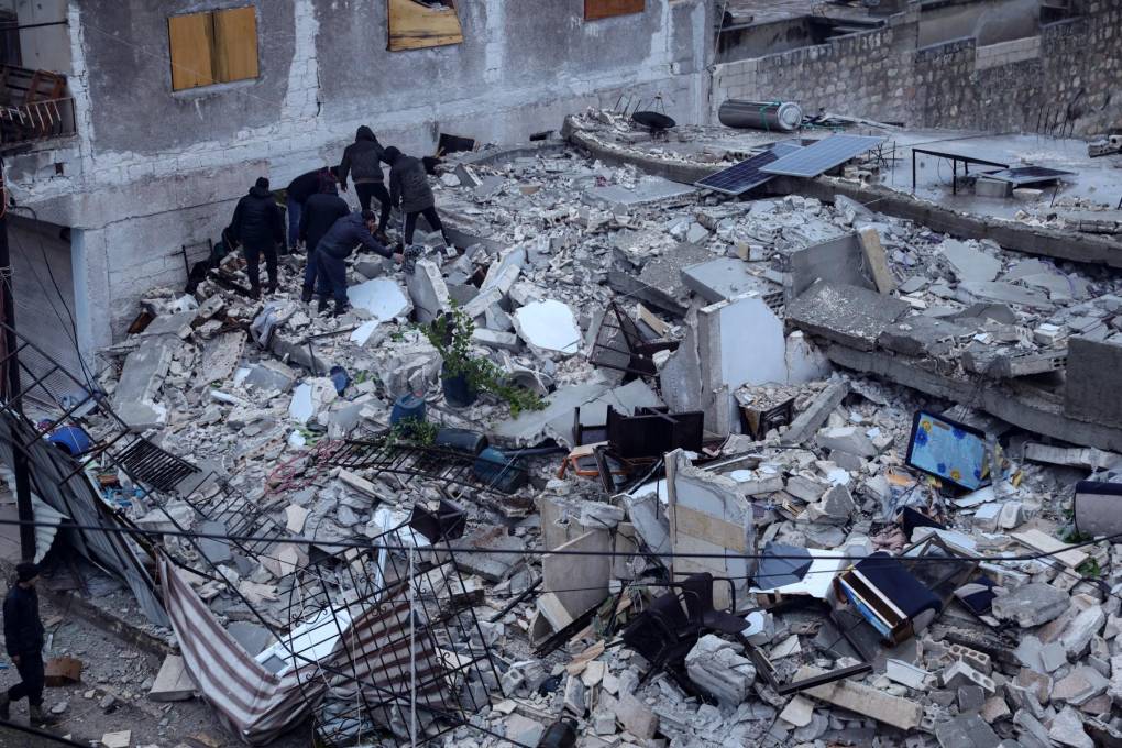 Los residentes buscan víctimas y sobrevivientes entre los escombros de un edificio que se derrumbó, luego de un terremoto en la aldea de Azmarin, cerca de la frontera turca.