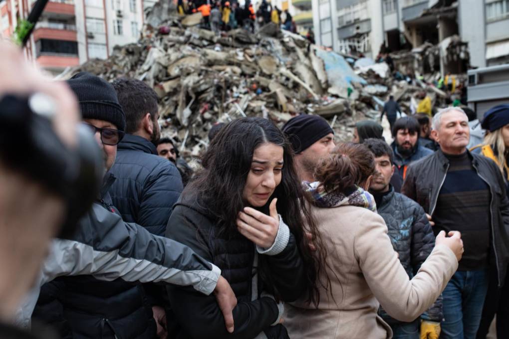 Una mujer reacciona mientras los rescatistas buscan supervivientes entre los escombros de los edificios derrumbados en Adana.