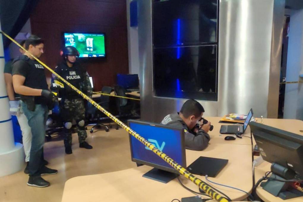 Policías recolectan evidencia después de que un artefacto detonase en las instalaciones de un canal Ecuavde televisión.
