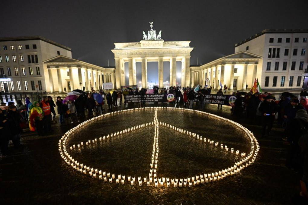 Forman un signo de paz gigante con velas frente a la Puerta de Brandenburgo en Berlín