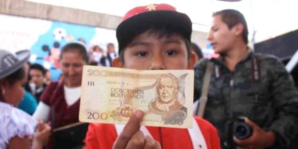 Un niño muestra un billete de Bs 200 del Bono Juancito Pinto.