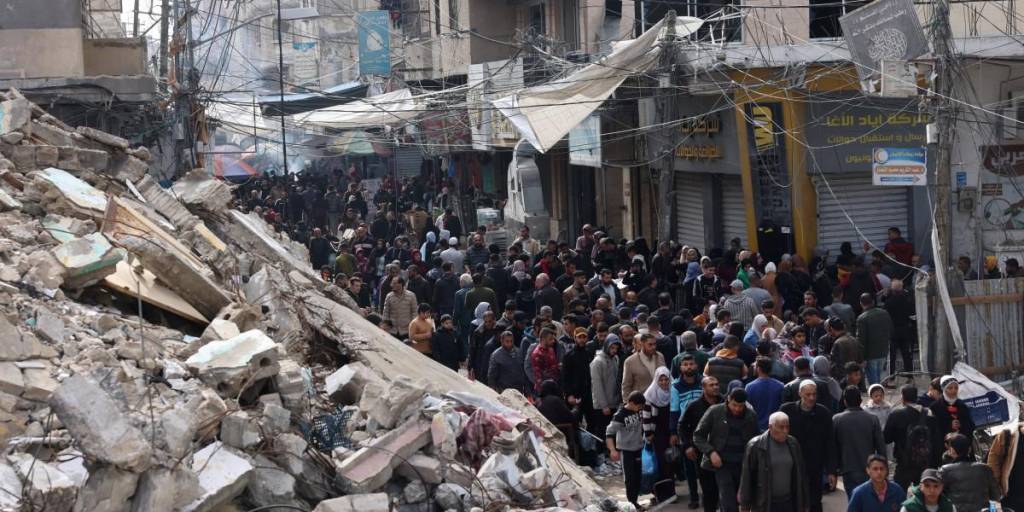 Multitudes de lugareños y palestinos desplazados pasan junto a edificios destruidos en la ciudad de Khan Yunis, en el sur de la Franja de Gaza.