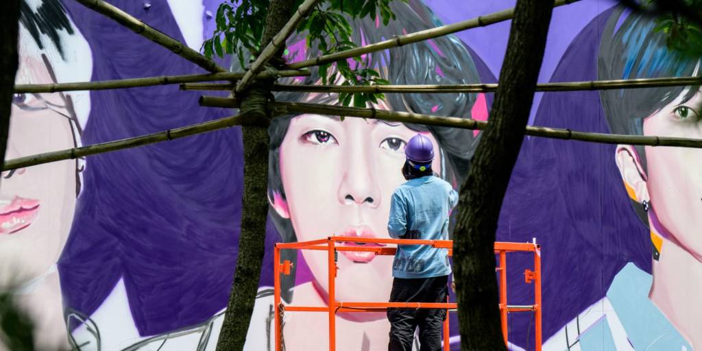 Un artista pinta con aerosol un mural de las megaestrellas del K-pop BTS en Seúl el 12 de junio de 2023.
