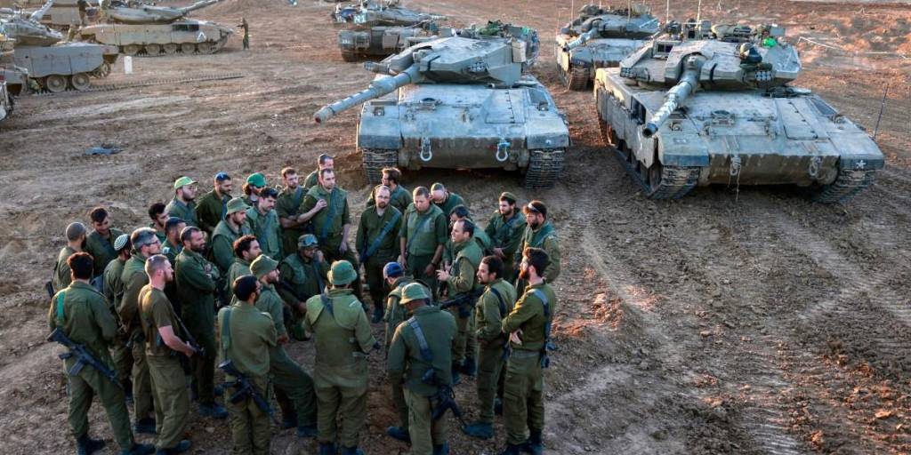 Soldados israelíes desplegados en la frontera sur con la Franja de Gaza el 29 de noviembre de 2023, se reúnen para una sesión informativa junto a tanques de batalla.