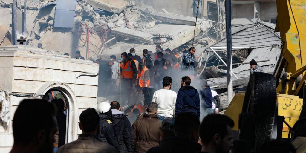 La gente y los rescatistas se reúnen frente a un edificio destruido en un ataque israelí en Damasco el 20 de enero de 2024.