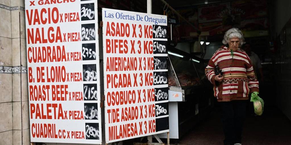 Una mujer pasa junto a un cartel con los precios de la carne en una carnicería en Buenos Aires.