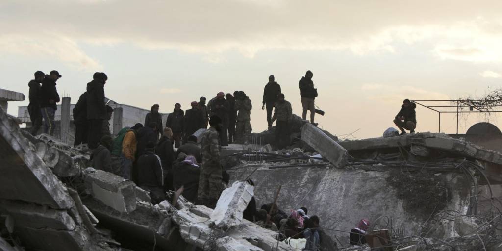 Rescatistas y civiles sirios se mueven entre los escombros de un edificio derrumbado el martes en la ciudad de Jandairis, mientras continúan las operaciones de búsqueda y rescate después del terremoto mortal.