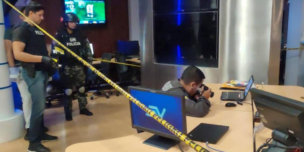 Policías recolectan evidencia después de que un artefacto detonase en las instalaciones de un canal Ecuavde televisión.
