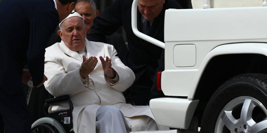El Papa Francisco habla con sus ayudantes antes de que lo ayuden a levantarse del carro papamóvil desde su silla de ruedas, cuando sale el 29 de marzo de 2023.