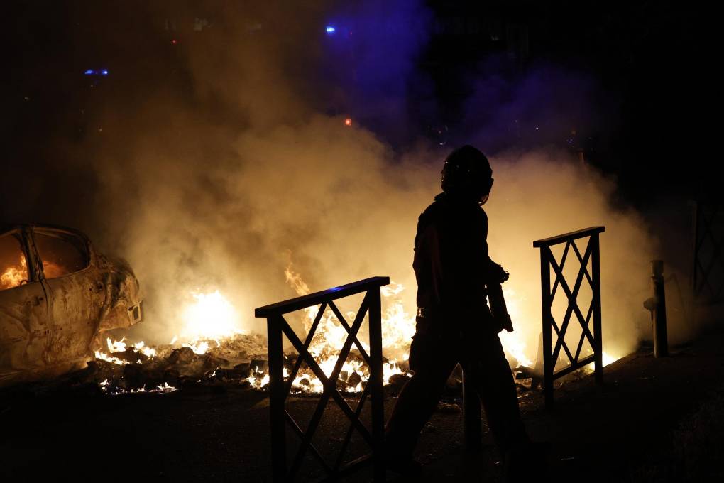 Un bombero apaga las llamas de un automóvil incendiado durante las protestas en Nanterre.