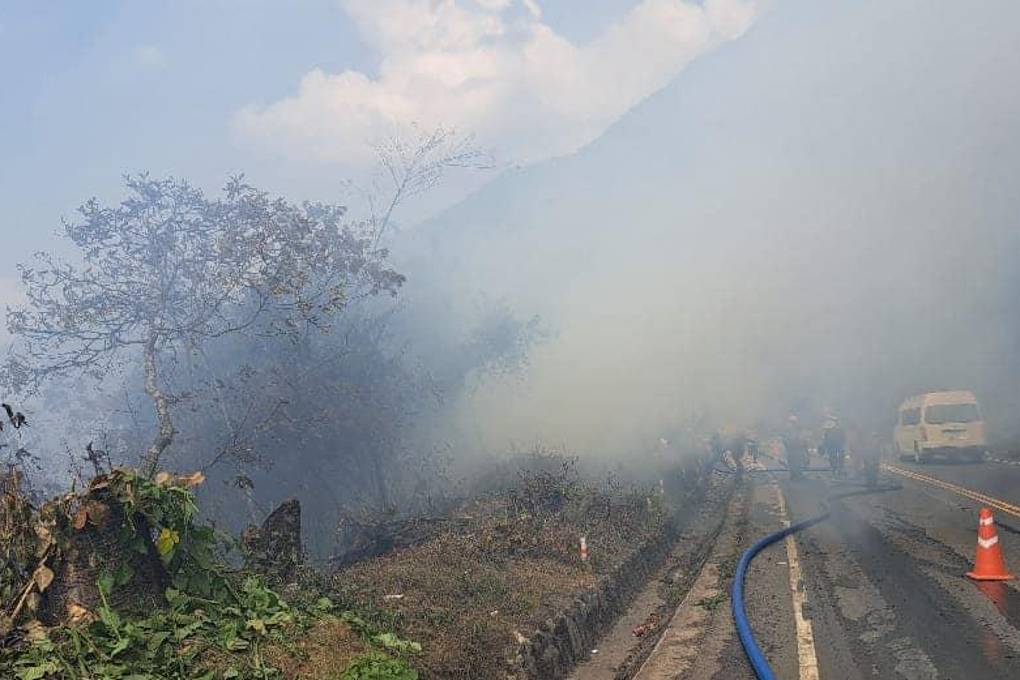 Los comunarios trabajan para aplacar las llamas en medio de una densa humareda.